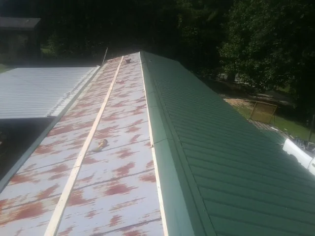 Old rusted panels beside newly installed green metal roofing — Wind Damage Roof Repair by Roofing Brothers in Crewe