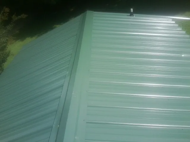 New green metal panels meeting at the ridge of a roof — Flat Roof Repair work by our crew in Crewe