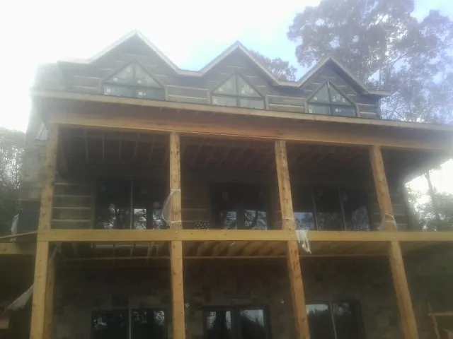 Dormers and porch framing on a large log home under construction — Roof Coating work by our crew in Crewe