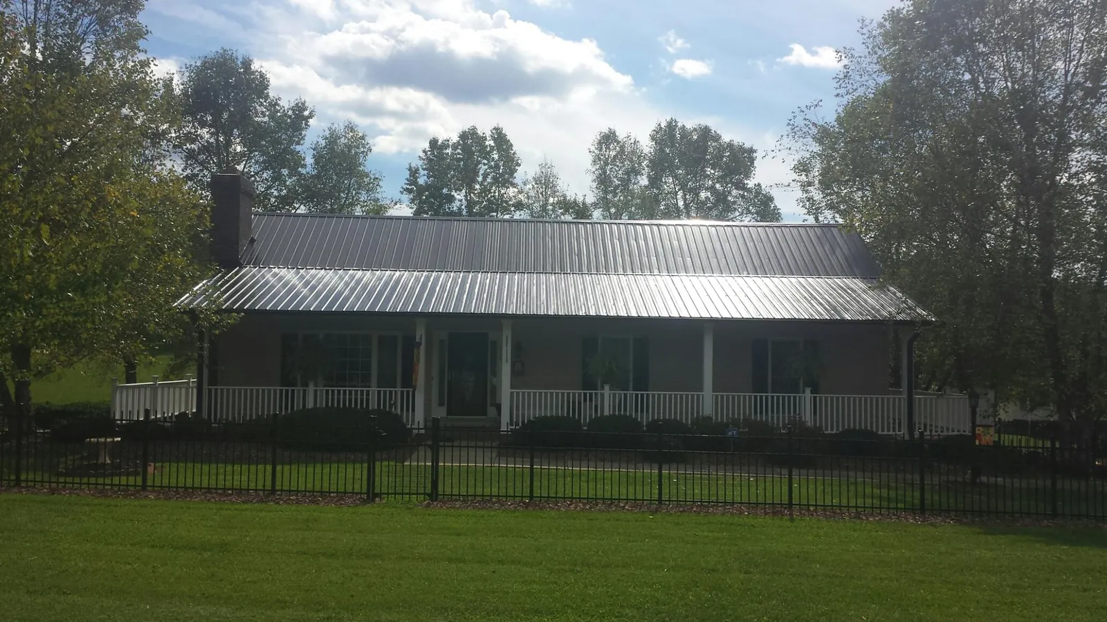 Gray metal roof on a brick ranch with a full width front porch — Gutter Guard Installation work by our crew in Crewe